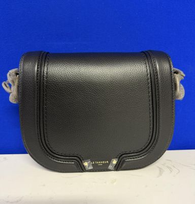 a black leather cross body bag on a white table