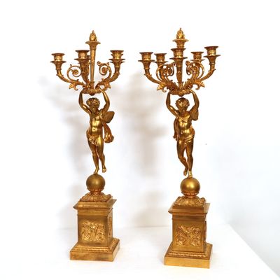 two gold colored candlesticks with angels on them