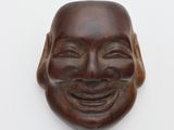 masque en bois représentant un homme souriant sur fond blanc