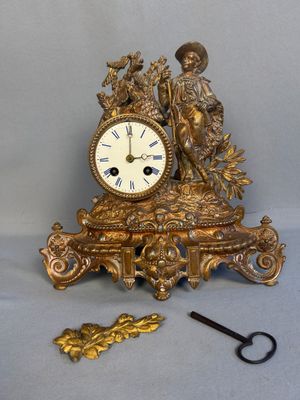 une horloge en or posée sur une table à côté d'une paire de ciseaux