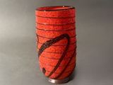 un vase rouge orné d'un motif noir