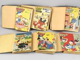 Six albums de la série « Walt Comics » sont alignés sur une table