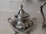 three silver teapots on display in a glass case