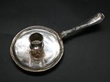 a silver saucer with a spoon on it on a black surface