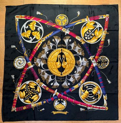 a black square scarf with gold and black designs on it