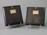 pair of black picture frames with a gold plaque on each of them