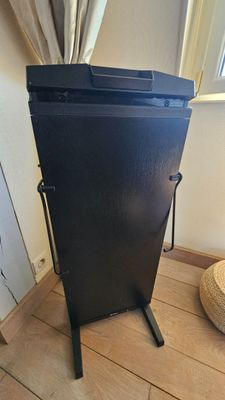 une armoire noire posée sur un parquet, près d'une fenêtre