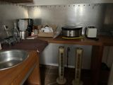 une cuisine équipée d'un évier, d'une cuisinière et d'autres éléments posés sur le plan de travail