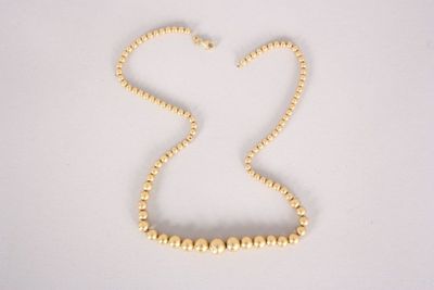 gold beaded necklace on a white background with a heart