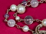 a close up of a necklace with pearls and a turtle on it