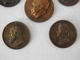 four bronze coins with portraits of men on them on a white surface