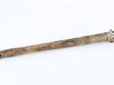 a wooden stick with a metal handle on a white surface