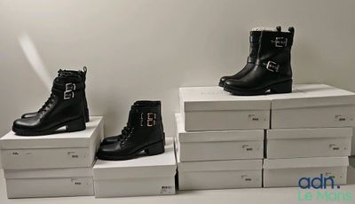 three pairs of black boots are sitting on top of white boxes
