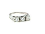 a close up of a three stone diamond ring on a white background