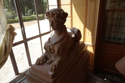 une statue représentant une femme assise sur un rebord de fenêtre