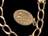a close up of a gold chain bracelet with a coin on it
