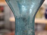 a blue glass vase sitting on a table in a room