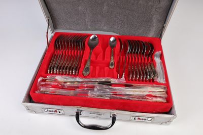 des couverts dans un coffret en argent posé sur une surface blanche