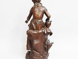 a bronze statue of a woman sitting on top of a rock