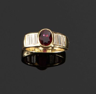 un gros plan sur une bague en or sertie d'une pierre rouge et de diamants taille baguette