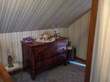 a dresser in the corner of a room under a slant roof