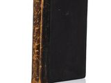 un vieux livre à la couverture noire posé sur une surface blanche