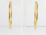 a pair of gold hoop earrings on a clear stand