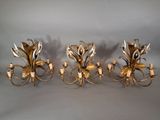 three antique brass wall sconces with flowers and leaves on them