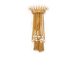 un gros plan sur une broche en or ornée de perles et de pompons