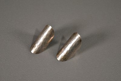 une paire de boucles d'oreilles en métal argenté sur un fond gris