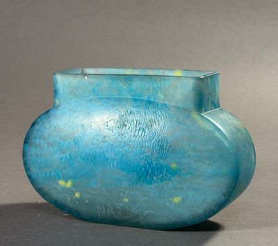 un vase bleu posé sur une table, sur fond gris