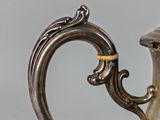 a silver tea pot with a gold handle on a table