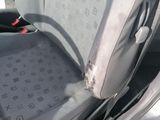 a dirty seat in the back of a car with a broken arm rest