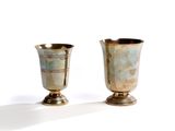 two silver vases sitting next to each other on a white surface