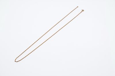 a gold necklace with a long chain on a white background