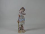 une figurine représentant une femme portant un chapeau et une robe