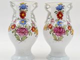 pair of white vases with floral designs on them against a white background