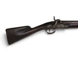 un vieux fusil exposé sur une surface blanche