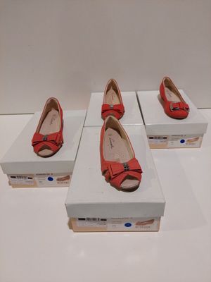 Trois paires de chaussures rouges sont exposées dans une boîte blanche