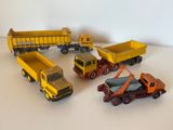 Plusieurs camions miniatures sont alignés sur une surface blanche