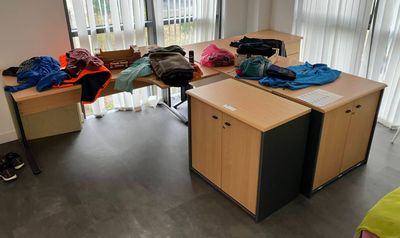 a desk with clothes on it in the corner of a room