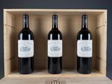 three bottles of red wine in a wooden box on a table