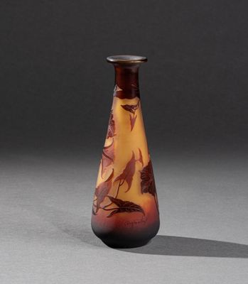 un vase orange et marron orné d'oiseaux, posé sur une surface grise