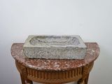 an old stone sink sitting on top of a table next to a white wall