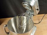 a mixer with a whisk inside of it on a wooden table