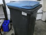 une poubelle noire avec un couvercle bleu dans un garage