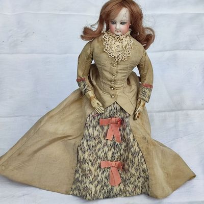 une poupée habillée d'une robe et d'un manteau