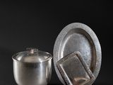 a silver cup and saucer sitting next to each other on a black background