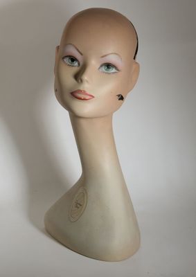 une tête de mannequin posée sur une table blanche