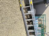 a ladder leaning up against a building next to a trash can